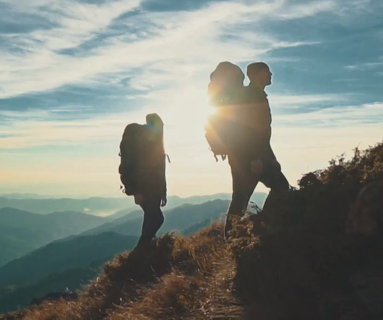 Two hikers on a mountain ridge at sunrise